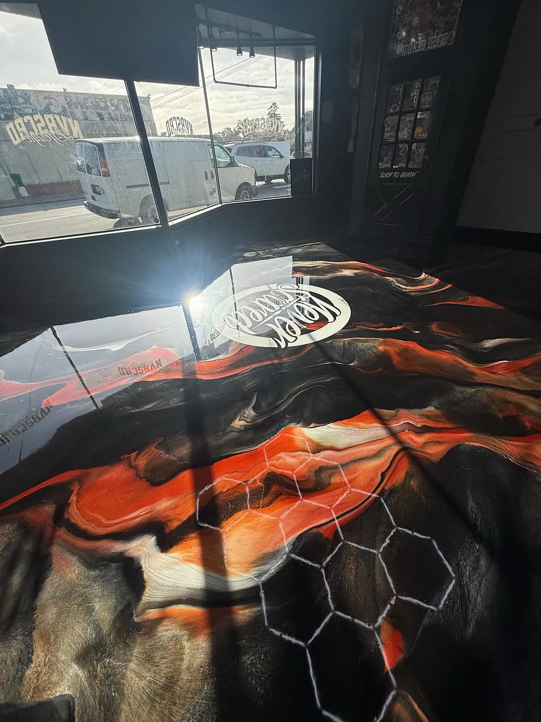 Custom seamless epoxy floor in a California tattoo studio with artistic metallic design