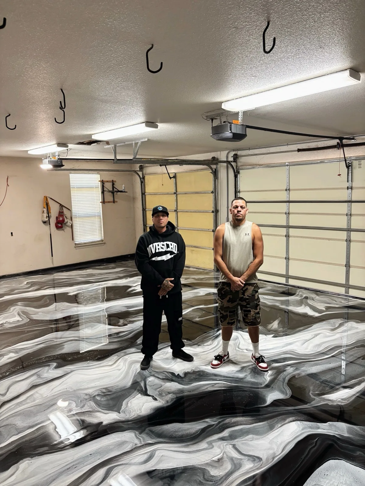 UFC fighter Nate Diaz standing on a black and white metallic epoxy garage floor poured by Gold Coast Resin