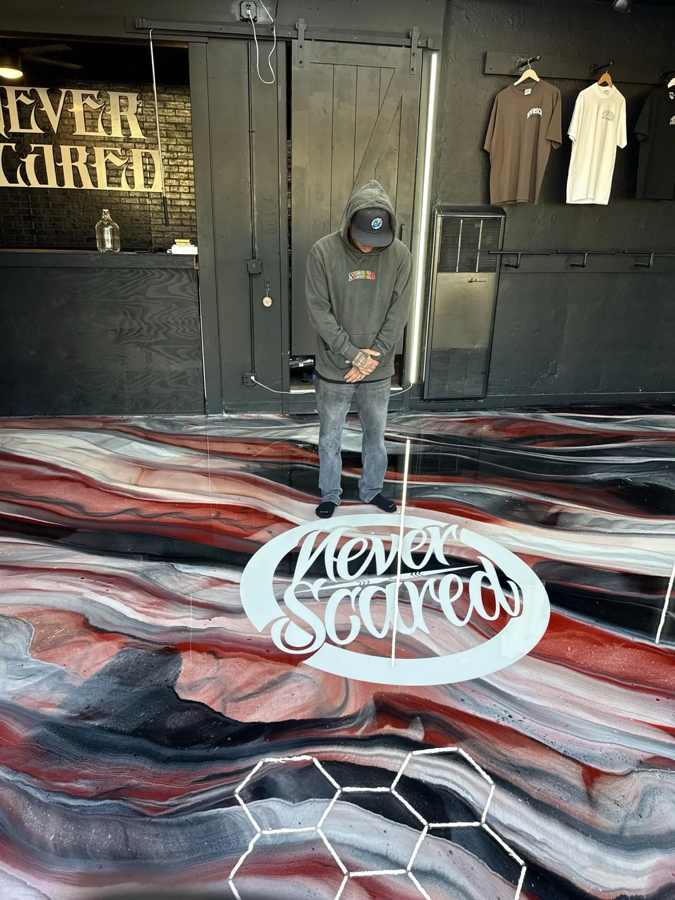 Never Scared script logo inlaid into a red, white and charcoal metallic epoxy floor inside the brand's retail space