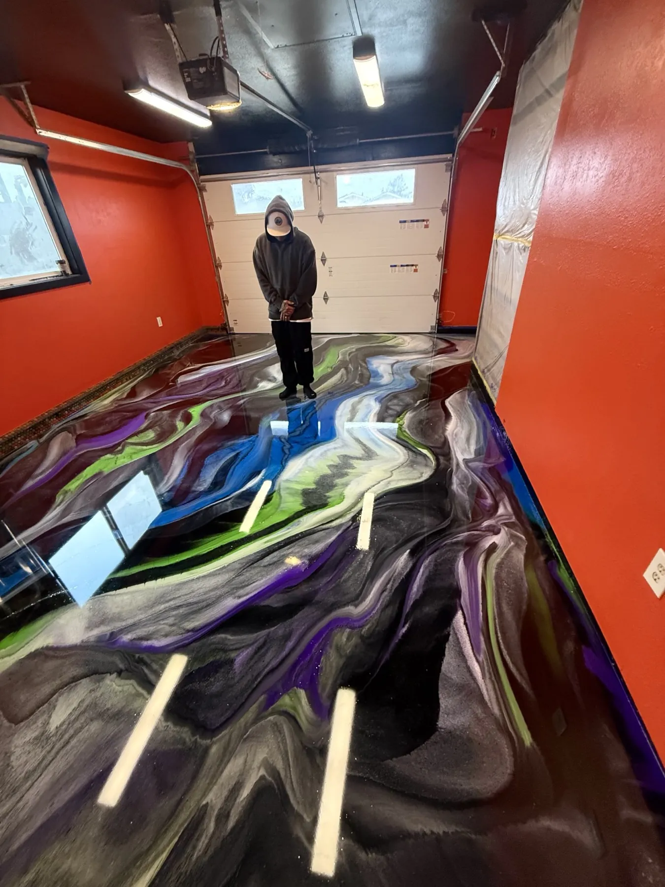 Purple, green and blue metallic epoxy garage floor with a river of color cutting through black marbling