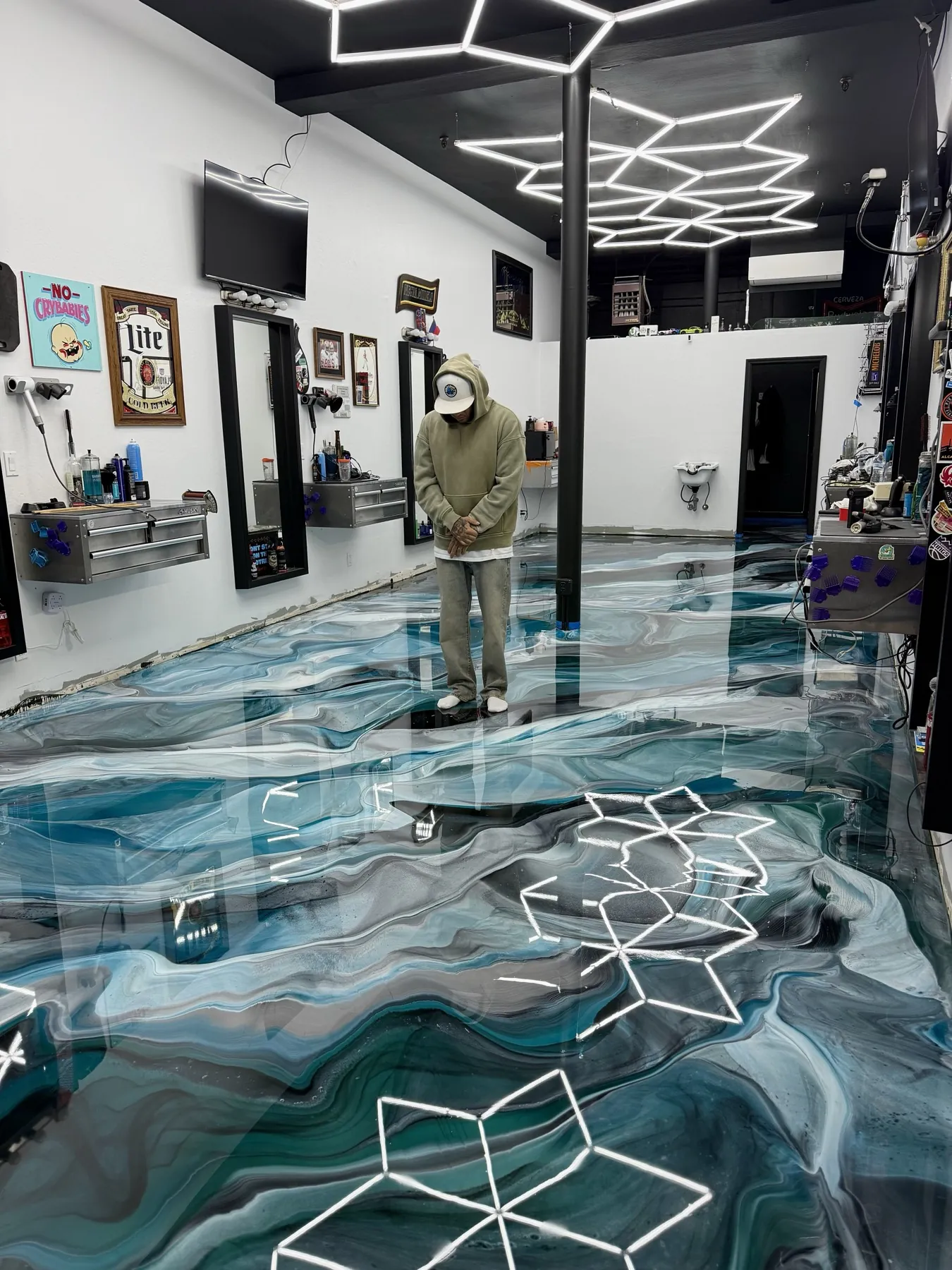 Teal and black metallic epoxy floor in a barbershop, hexagon light fixtures reflecting off the gloss